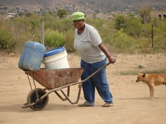 A woman carrying water from the community well in the Loraine Community